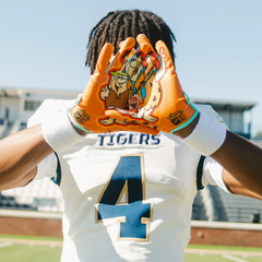 Phenom Elite Flintstones football gloves lifestyle photo — orange Bedrock Blitz gloves on field